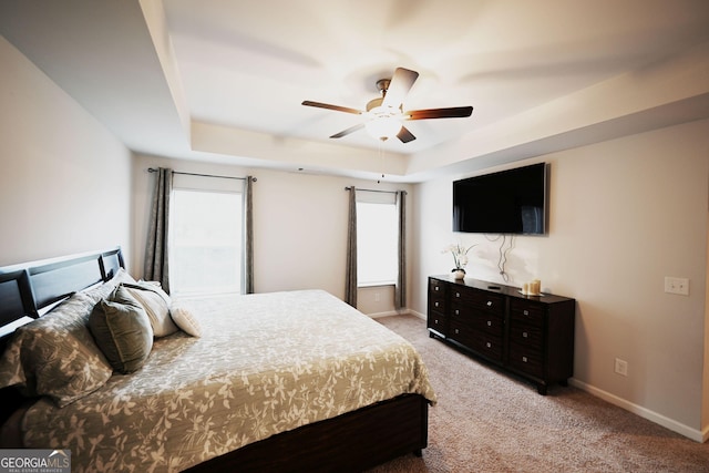 bedroom with a ceiling fan, a raised ceiling, carpet flooring, and baseboards