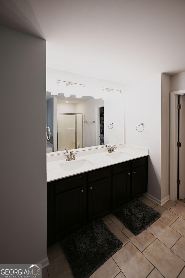 bathroom featuring a stall shower, tile patterned flooring, a sink, and double vanity