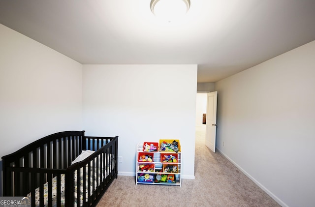 bedroom with light carpet, a nursery area, and baseboards