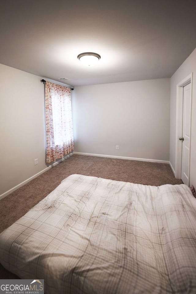 unfurnished bedroom with dark colored carpet and baseboards