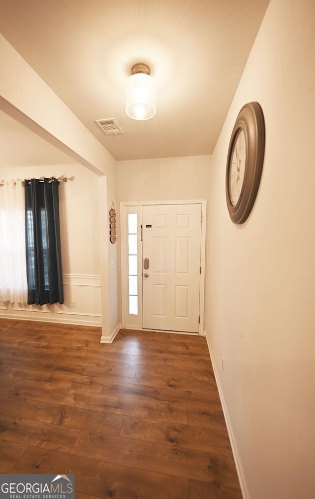 foyer with baseboards, visible vents, and dark wood finished floors