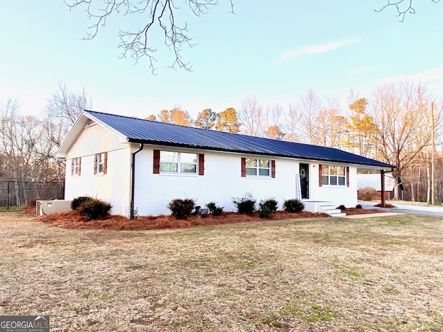 ranch-style house with a front yard, metal roof, and brick siding