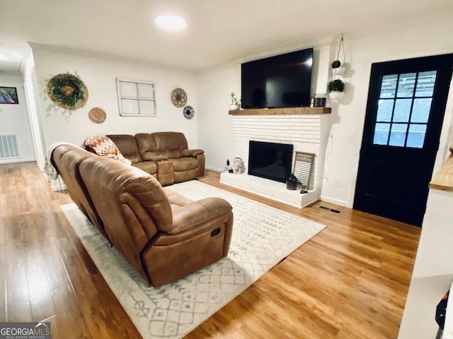 living room featuring baseboards, a fireplace, visible vents, and wood finished floors