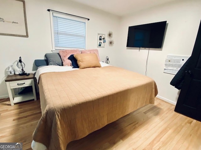 bedroom featuring light wood finished floors and baseboards