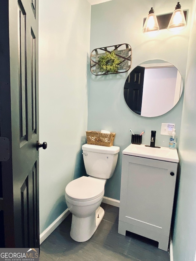 half bathroom with baseboards, vanity, toilet, and wood finished floors