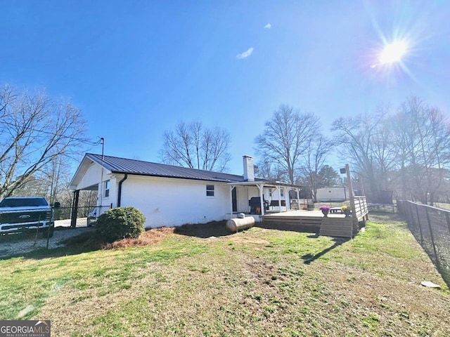 rear view of property with metal roof, a yard, a chimney, and fence