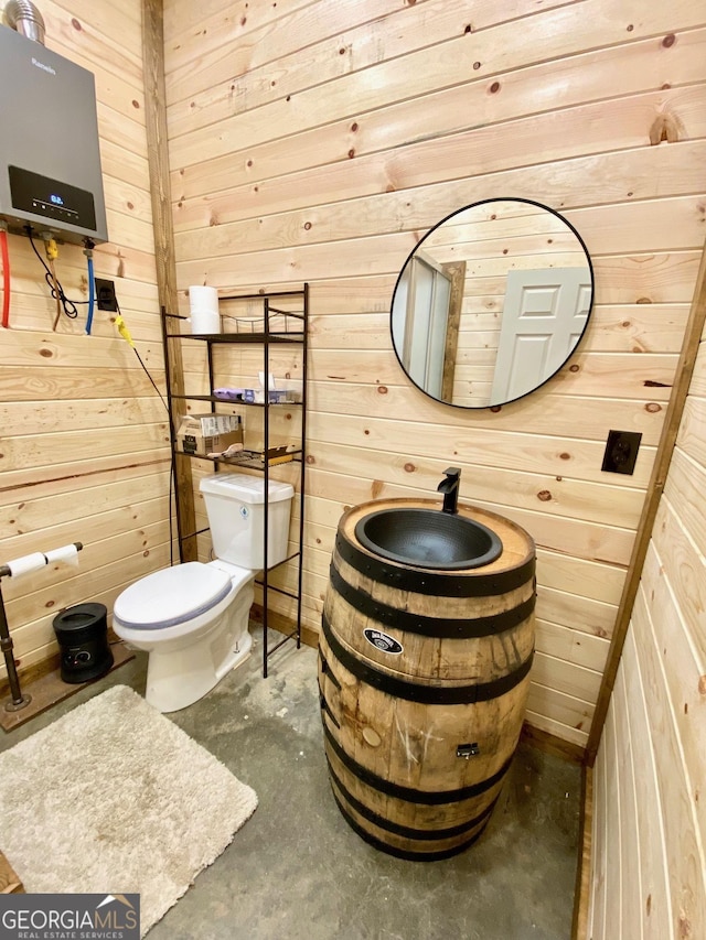 half bathroom featuring concrete flooring, wood walls, vanity, and toilet