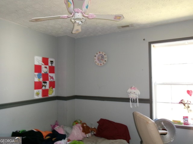 bedroom featuring a ceiling fan, visible vents, and a textured ceiling