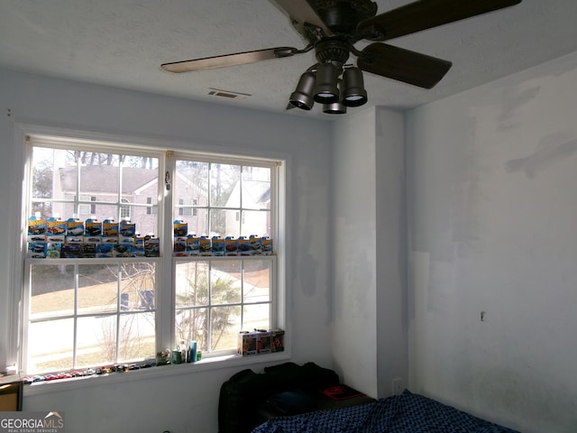 room details featuring a textured ceiling, visible vents, and a ceiling fan