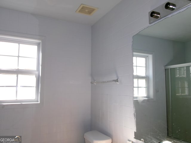 bathroom featuring toilet, a stall shower, and visible vents