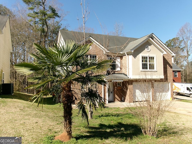 view of front of house featuring brick siding, concrete driveway, an attached garage, central air condition unit, and a front yard