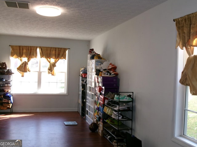 interior space with a wealth of natural light, visible vents, dark wood finished floors, and a textured ceiling