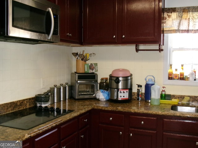 kitchen with reddish brown cabinets, stainless steel microwave, and black electric cooktop