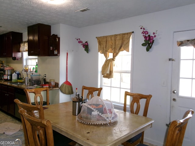 dining room featuring a wealth of natural light, visible vents, and a textured ceiling