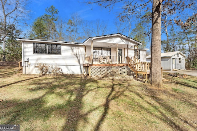 manufactured / mobile home with covered porch, a front lawn, and an outbuilding