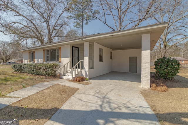 ranch-style house featuring driveway, an attached carport, and stucco siding