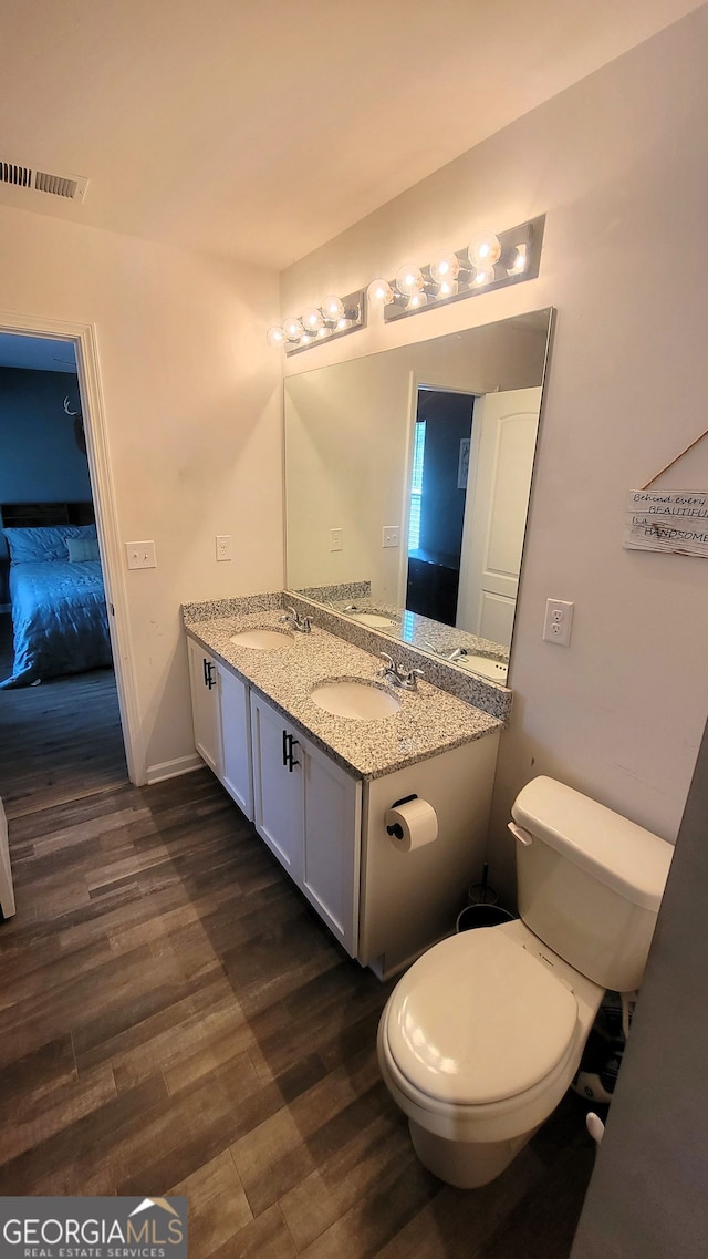 bathroom featuring toilet, wood finished floors, a sink, and visible vents