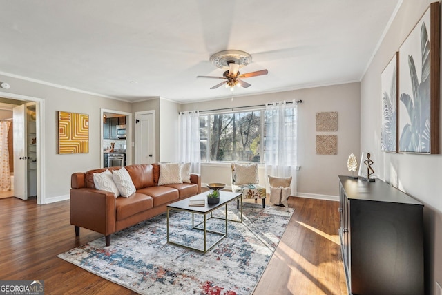 living room with baseboards, ornamental molding, ceiling fan, and dark wood-type flooring