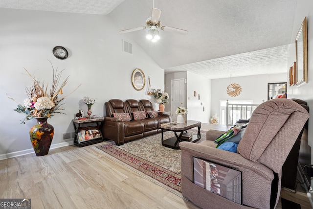 living area with light wood-type flooring, visible vents, a textured ceiling, and baseboards