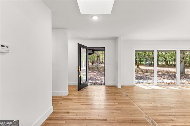 entryway with recessed lighting, a skylight, light wood-style flooring, and baseboards