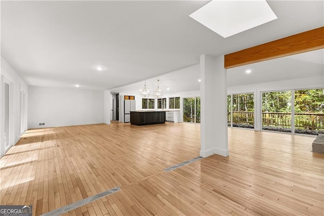 unfurnished living room with light wood-style floors, vaulted ceiling with skylight, and recessed lighting
