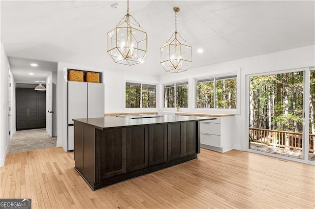 kitchen featuring dark brown cabinetry, a kitchen island, light wood-style flooring, and a healthy amount of sunlight