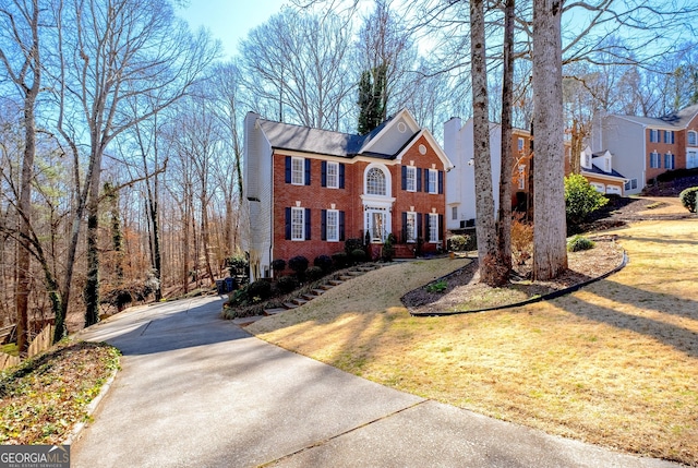 view of front of house with a front yard, brick siding, and a chimney