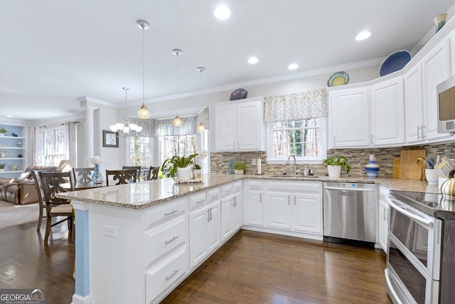 kitchen with a peninsula, a sink, white cabinetry, appliances with stainless steel finishes, and pendant lighting