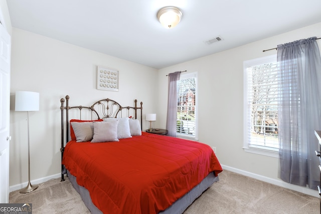 bedroom with multiple windows, visible vents, and light colored carpet