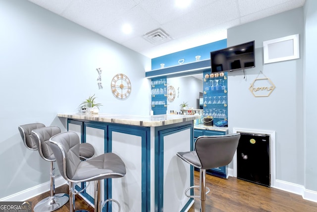 bar with baseboards, visible vents, dark wood finished floors, wet bar, and a paneled ceiling