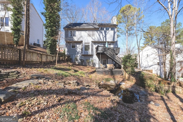 rear view of house featuring a chimney, stairs, fence, and a deck