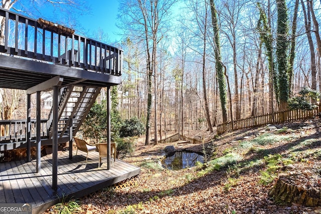 view of yard featuring fence, a wooden deck, and stairs