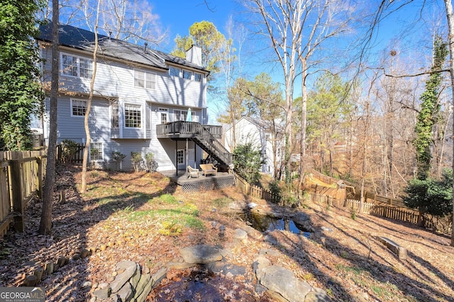 back of house featuring stairway, a chimney, a fenced backyard, and a deck