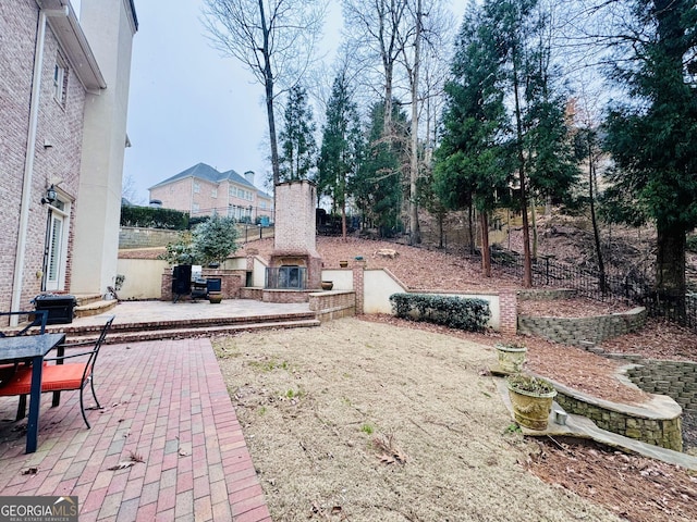 view of yard featuring a patio and an outdoor fireplace