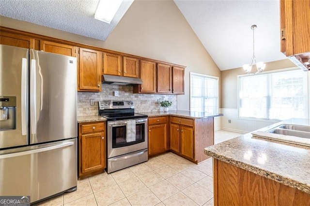 kitchen with brown cabinets, light stone countertops, stainless steel appliances, under cabinet range hood, and pendant lighting