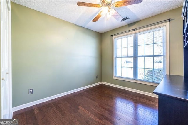 spare room with a textured ceiling, dark wood-type flooring, and visible vents