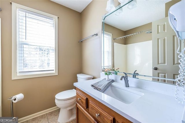 bathroom with toilet, vanity, baseboards, and tile patterned floors