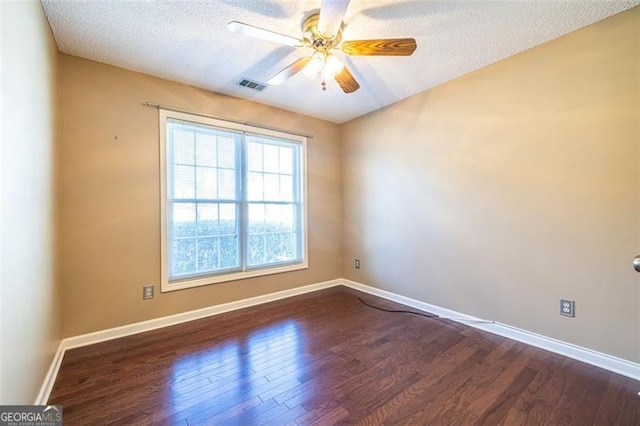 spare room featuring dark wood-style floors, visible vents, ceiling fan, a textured ceiling, and baseboards