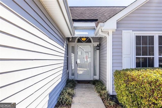 view of exterior entry with a shingled roof