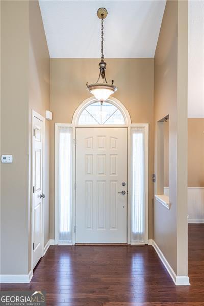 foyer entrance featuring dark wood-style floors, a high ceiling, and baseboards