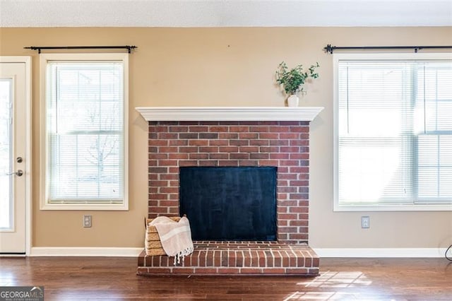 interior space with a textured ceiling, a fireplace, wood finished floors, and baseboards