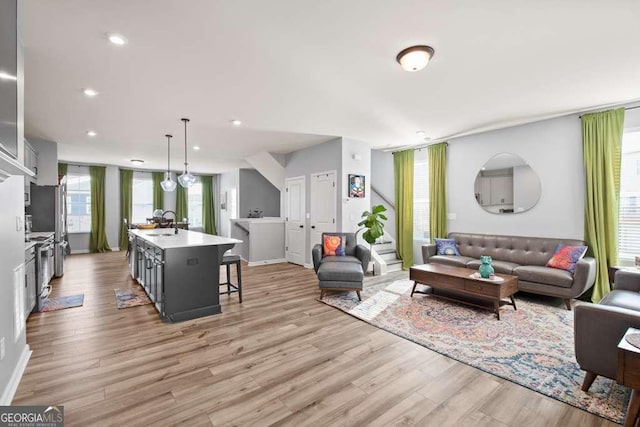 living area featuring light wood-type flooring, baseboards, and recessed lighting