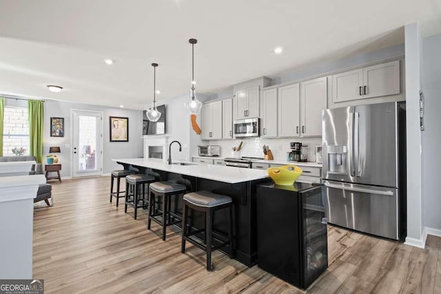 kitchen featuring a sink, a center island with sink, stainless steel appliances, and light countertops