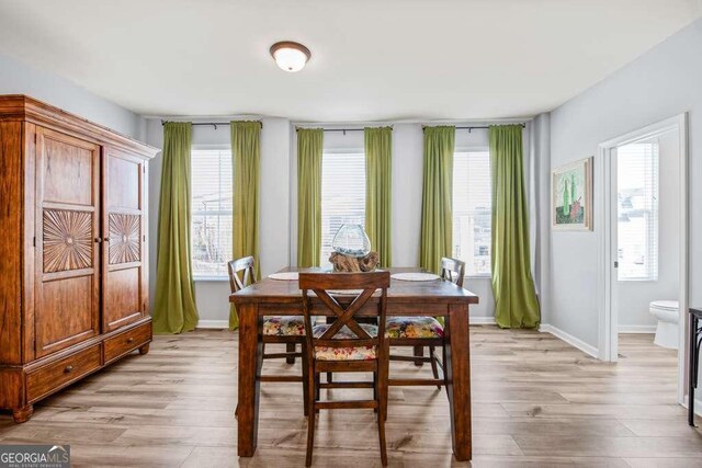 dining area with a healthy amount of sunlight, light wood finished floors, and baseboards