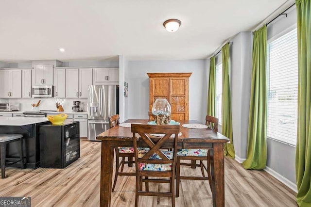 dining space featuring light wood-type flooring, a toaster, and baseboards