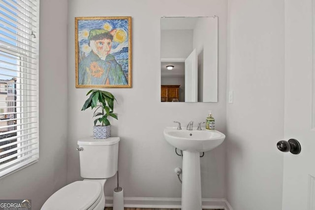 half bath featuring baseboards, a sink, and toilet