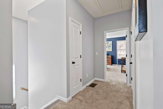 corridor with light carpet, baseboards, and visible vents