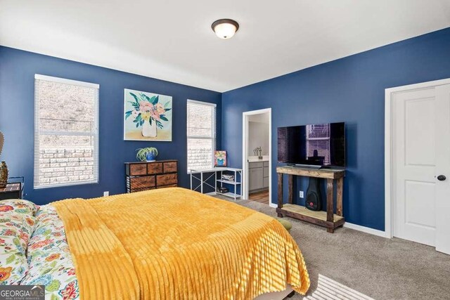 carpeted bedroom with ensuite bath and baseboards