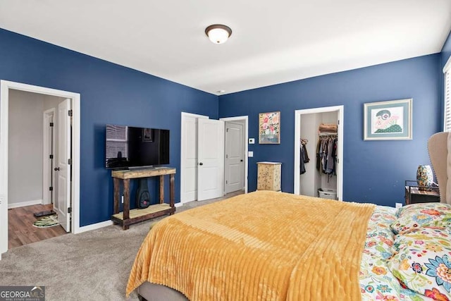 bedroom featuring a spacious closet, a closet, carpet, and baseboards