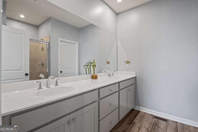 bathroom featuring a shower stall, visible vents, a sink, and wood finished floors